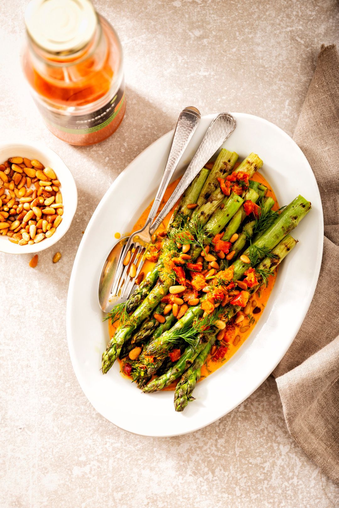 Gegrilde groene asperges met wortel-knoflookjus, dille en pijnboompitten