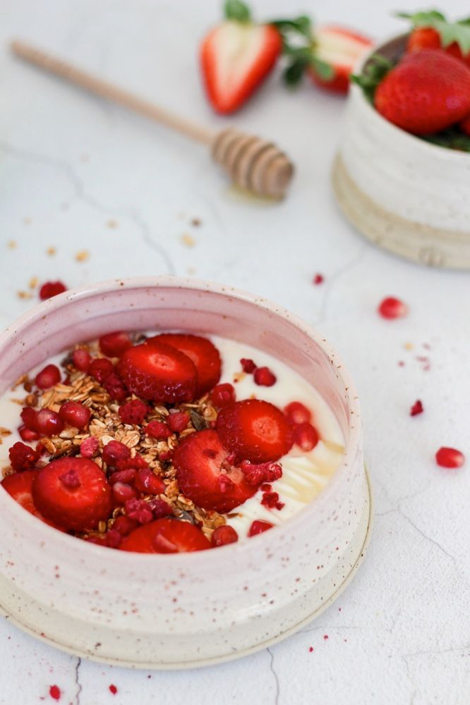 Yoghurt granola bowl met aardbeien, granaatappel en framboos